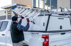 man loading a ladder onto the ladder rack on his work vehicle