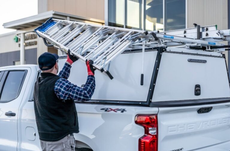 man loading a ladder onto the ladder rack on his work vehicle